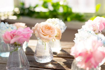 Decoration of blooming blue hydrangea, sweet pea Lathyrus, bush roses in small crystal vases on wooden background. Design,creative.International Women's Day,March 8 and Valentine's Day,14 of February