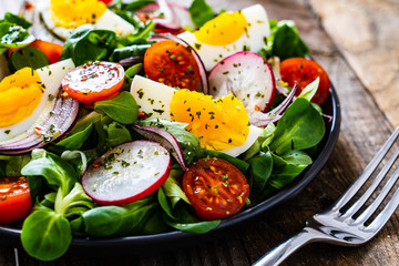 Salad with boiled egg and vegetables on wooden table
