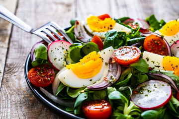 Salad with boiled egg and vegetables on wooden table
