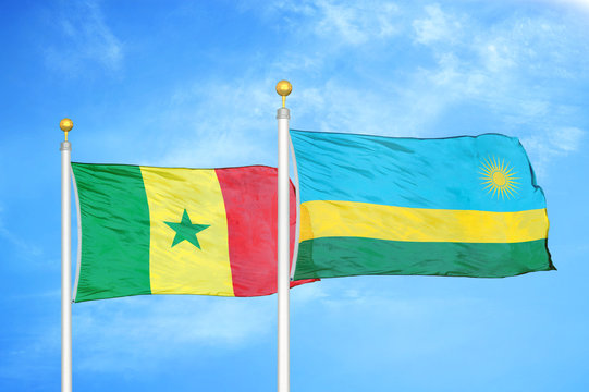 Senegal and Rwanda two flags on flagpoles and blue cloudy sky