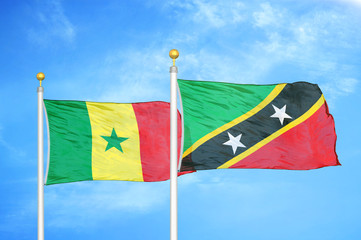 Senegal and Saint Kitts and Nevis two flags on flagpoles and blue cloudy sky