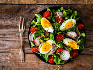 Salad with boiled egg and vegetables on wooden table
