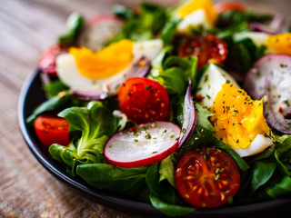 Salad with boiled egg and vegetables on wooden table
