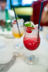 Two glasses of cocktails with blurry background of bartender.