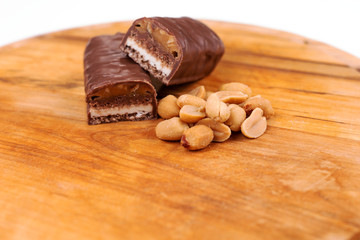 Chocolate peanut butter energy bar with peanuts on the wooden board