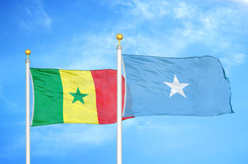 Senegal and Somalia two flags on flagpoles and blue cloudy sky