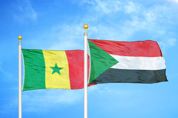 Senegal and Sudan two flags on flagpoles and blue cloudy sky