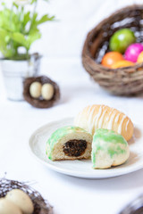 gefüllte bunte und farbige Eier aus Hefe mit Zuckerguss zu Ostern auf Teller auf weißer Decke