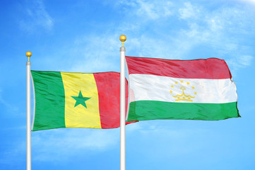 Senegal and Tajikistan two flags on flagpoles and blue cloudy sky