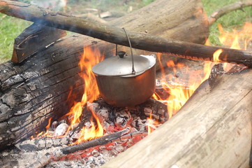 Cooking on an open fire in field conditions. Boiling water in the bowler on the bonfire. Close-up....