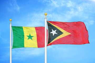 Senegal and Timor-Leste East Timor two flags on flagpoles and blue cloudy sky