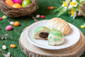 gefüllte bunte und farbige Eier aus Hefe mit Zuckerguss zu Ostern auf Teller und grünem Gras Grund