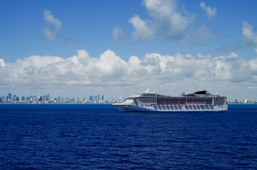 Huge modern cruiseship or cruise ship liner at sea with skyline of Miami or South Beach SOBE in...
