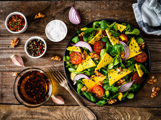 Fresh salad - blue cheese, cherry tomatoes, vegetables and walnuts on wooden background