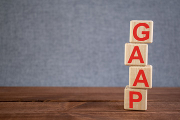 Abbreviation GAAP (Generally Accepted Accounting Principles) text acronym on wooden cubes on dark wooden backround. Business concept.