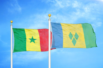 Senegal and Saint Vincent and the Grenadines two flags on flagpoles and blue sky