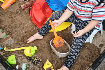 cute asian little girl playing with toys in sandbox having fun feeling happy and enjoying play time, staying at home out door making mess and using imagination for learning doing practical activities