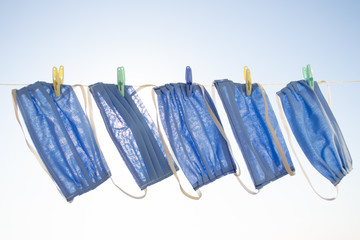 Reusable face masks are dried on a clothesline against a blue sky