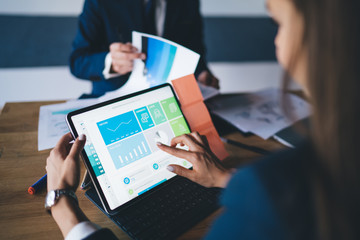Cropped image of female professional checking financial website with revenue statistics and...