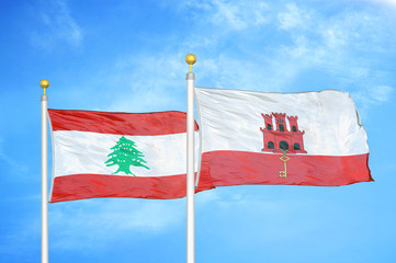 Lebanon and Gibraltar two flags on flagpoles and blue cloudy sky