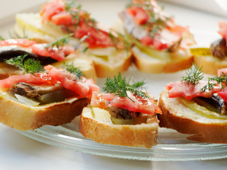 Snack sandwich with sprats cucumber and tomatoes and dill. Delicious sandwiches on a plate.
