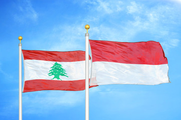 Lebanon and Indonesia two flags on flagpoles and blue cloudy sky