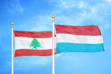 Lebanon and Luxembourg two flags on flagpoles and blue cloudy sky