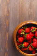 wooden dish with strawberries. wood background, top view, space for a text, vertical frame