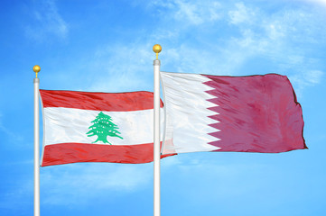 Lebanon and Qatar two flags on flagpoles and blue cloudy sky