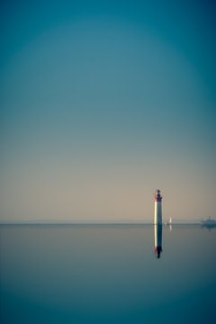 lighthouse and its reflections on a very quiet sea. format portrait 