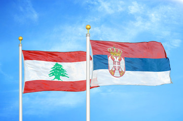 Lebanon and Serbia two flags on flagpoles and blue cloudy sky
