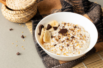 White plate with oatmeal porridge served with chokolate and banana