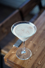 White creamy alcoholic cocktail in martini glass in a loft bar