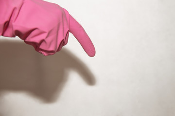 A pink glove dressed on a hand shows a finger down on a white background