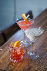 Creamy baileys cocktail, negroni and cosmopolitan on wooden bar counter in a loft bar