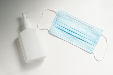 hand gel disinfectant bottle and medical mask on a white background
