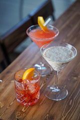 Creamy baileys cocktail, negroni and cosmopolitan on wooden bar counter in a loft bar