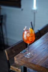 Aperol spritz with a slice of orange on wooden bar counter, atmospheric shot