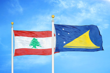 Lebanon and Tokelau two flags on flagpoles and blue cloudy sky