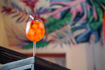 Aperol spritz cocktail with ice and orange on tropical background in a bar