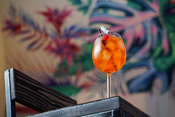 Aperol spritz cocktail with ice and orange on tropical background in a bar