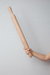 Children's hand holds a rolling pin for rolling dough