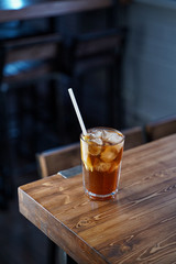 Modern classics mixology: cuba libre with rum and cola on wooden bar counter, atmospheric shot