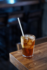 Modern classics mixology: cuba libre with rum and cola on wooden bar counter, atmospheric shot