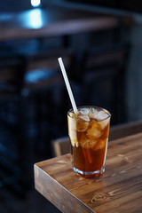 Modern classics mixology: cuba libre with rum and cola on wooden bar counter, atmospheric shot