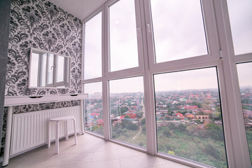 Large panoramic window with views of the city from above and bedside table with mirror
