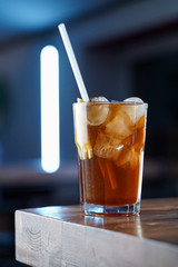 Modern classics mixology: cuba libre with rum and cola on wooden bar counter, atmospheric shot