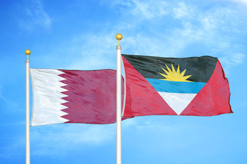Qatar and Antigua and Barbuda  two flags on flagpoles and blue cloudy sky