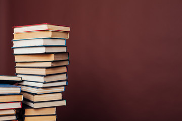 many stacks of educational books for learning the preparation for exams on a brown background
