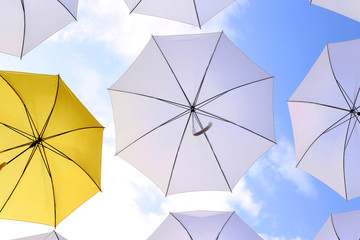 yellow and white umbrellas open against the blue sky